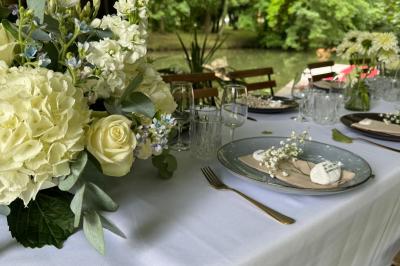 Tables dressées avec nappes blanches, vaisselle élégante, verres à pied et décorations florales sous des tonnelles…