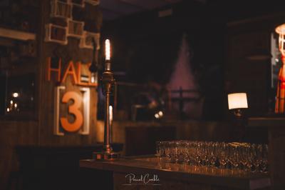 Un chandelier avec des bougies allumées posé près d'une ancienne presse métallique dans un décor artistique.