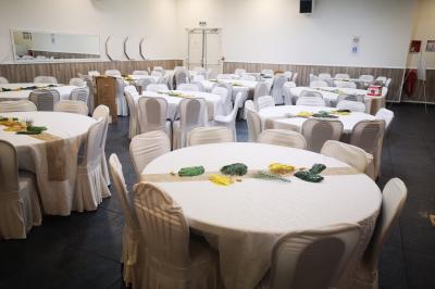 Salle de réception décorée avec des tables dressées, des ballons noirs et dorés, et des cordons rouges.