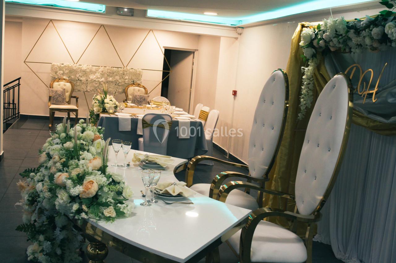 Salle de réception décorée avec des fleurs blanches et des chaises élégantes, prête pour un événement festif.