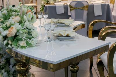 Salle de réception décorée avec des tables dressées, des ballons noirs et dorés, et des cordons rouges.