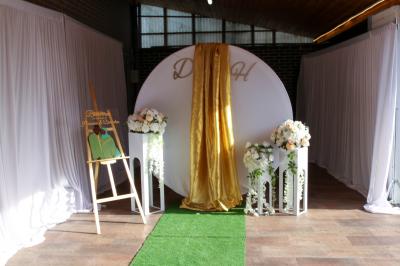 Salle de réception décorée avec des tables dressées, des ballons noirs et dorés, et des cordons rouges.