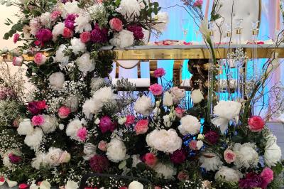 Salle de réception décorée avec des tables dressées, des ballons noirs et dorés, et des cordons rouges.