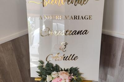 Salle de réception décorée avec des tables dressées, des ballons noirs et dorés, et des cordons rouges.