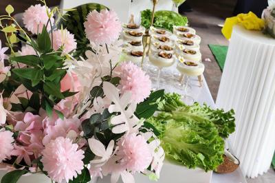 Salle de réception décorée avec des tables dressées, des ballons noirs et dorés, et des cordons rouges.