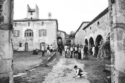 Salle en pierre avec tables rondes dressées pour un événement, décorée de lanternes suspendues et de fleurs.