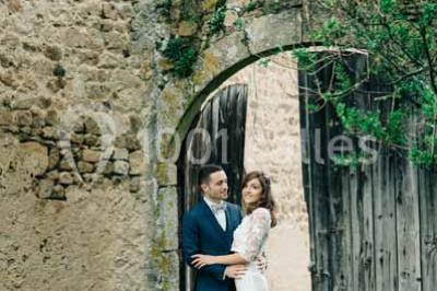 Salle en pierre avec tables rondes dressées pour un événement, décorée de lanternes suspendues et de fleurs.