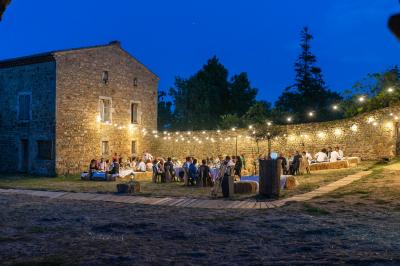 Salle en pierre avec tables rondes dressées pour un événement, décorée de lanternes suspendues et de fleurs.