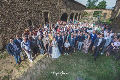 Salle en pierre avec tables rondes dressées pour un événement, décorée de lanternes suspendues et de fleurs.