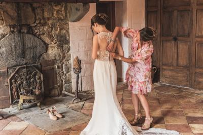 Salle en pierre avec tables rondes dressées pour un événement, décorée de lanternes suspendues et de fleurs.