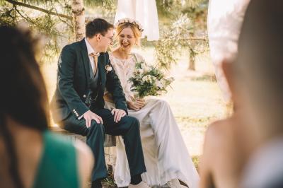Salle en pierre avec tables rondes dressées pour un événement, décorée de lanternes suspendues et de fleurs.