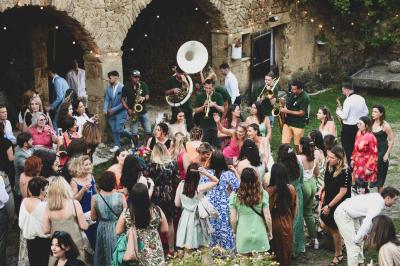 Salle en pierre avec tables rondes dressées pour un événement, décorée de lanternes suspendues et de fleurs.