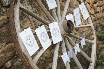 Groupe de personnes rassemblées dans une cour en pierre, certaines tenant des feuilles, ambiance festive en extérieur.