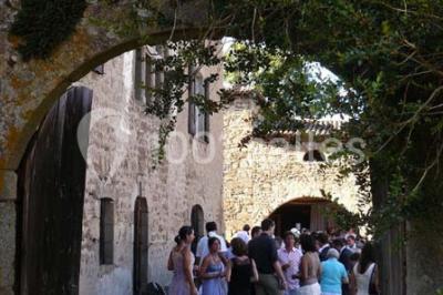 Salle en pierre avec tables rondes dressées pour un événement, décorée de lanternes suspendues et de fleurs.