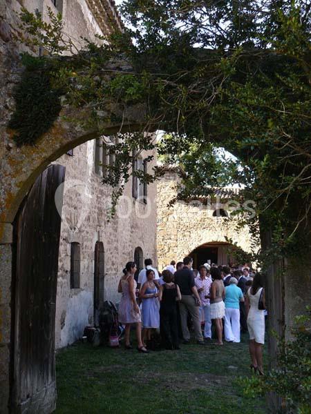 Un groupe de personnes rassemblées dans une cour en pierre, entourée de bâtiments anciens et de végétation.