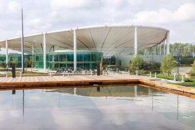 Bâtiment moderne avec une structure en toit incurvé, entouré de végétation et éclairé au crépuscule.