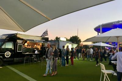 Bâtiment moderne avec une structure en toit incurvé, entouré de végétation et éclairé au crépuscule.