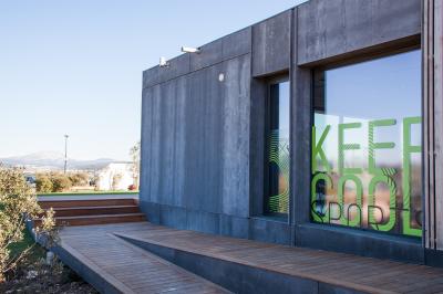 Bâtiment moderne avec une structure en toit incurvé, entouré de végétation et éclairé au crépuscule.