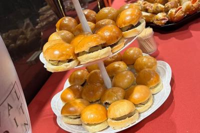 Escalier décoré de guirlandes lumineuses, de feuillage vert et de nœuds rouges, avec des sacs cadeaux posés sur les marches.
