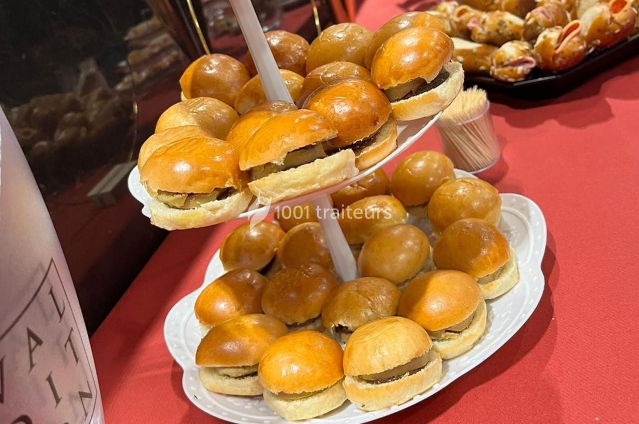 Plateau de mini-burgers disposés sur un présentoir à deux étages, posé sur une nappe rouge.