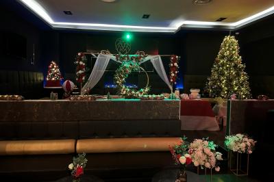 Escalier décoré de guirlandes lumineuses, de feuillage vert et de nœuds rouges, avec des sacs cadeaux posés sur les marches.