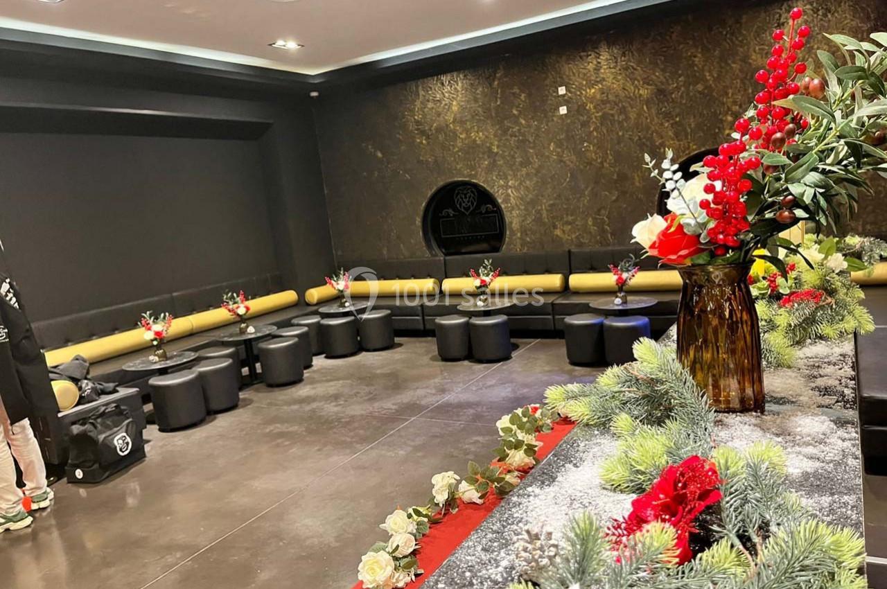 Salle moderne avec banquettes noires et jaunes, décorations florales et végétales sur une table au premier plan.