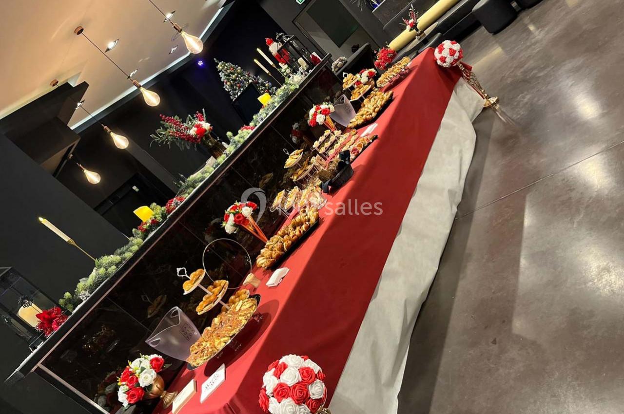 Table décorée avec des nappes rouges et blanches, garnie de desserts variés dans un espace intérieur festif.