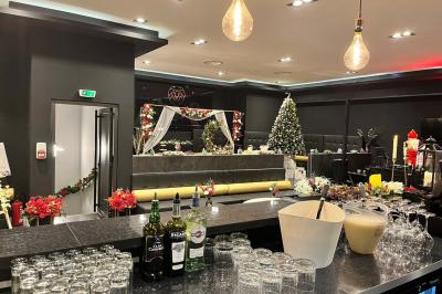 Escalier décoré de guirlandes lumineuses, de feuillage vert et de nœuds rouges, avec des sacs cadeaux posés sur les marches.