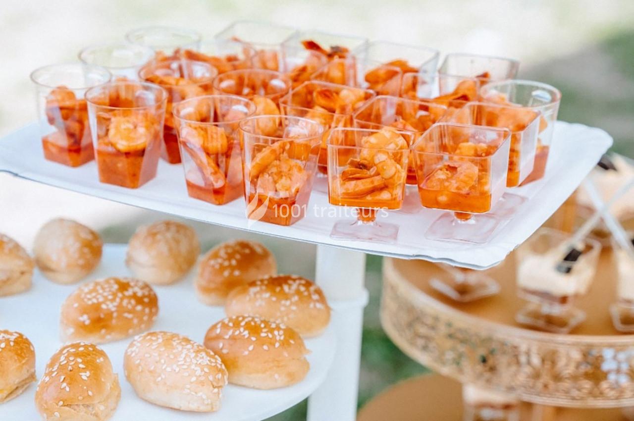 Plateau de verrines de crevettes en sauce et petits pains au sésame disposés sur une table lors d'un événement.