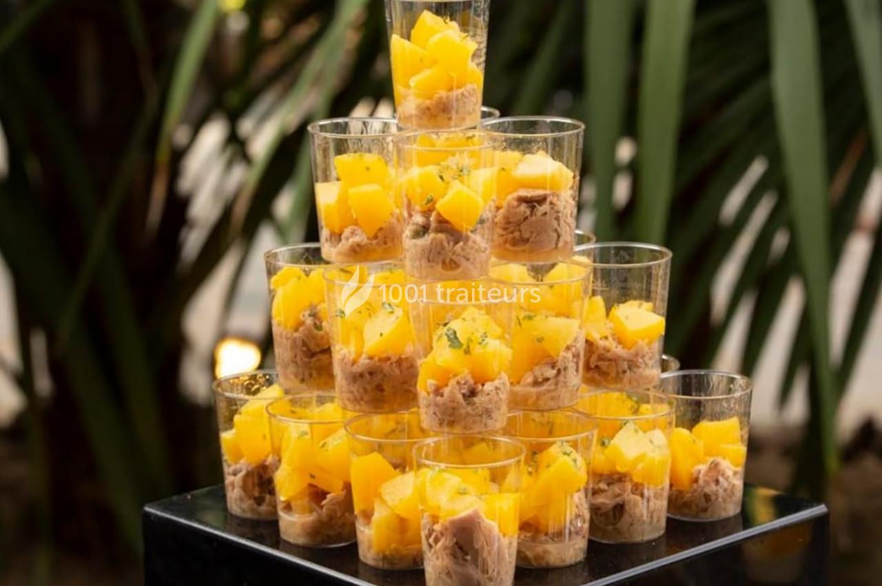 Verrines empilées contenant des morceaux de mangue et une préparation à base de thon, disposées en pyramide.