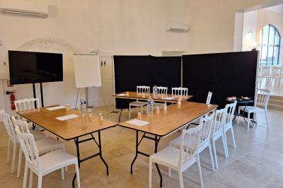 Salle de conférence lumineuse avec rangées de chaises blanches, un pupitre et un micro au premier plan.