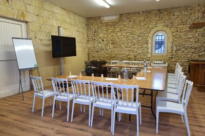 Salle de conférence lumineuse avec rangées de chaises blanches, un pupitre et un micro au premier plan.