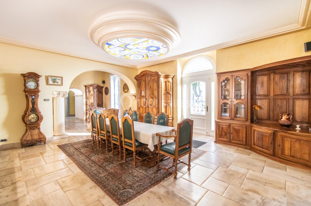 Salle à manger lumineuse avec une grande table entourée de chaises, meubles en bois et un plafond décoratif.