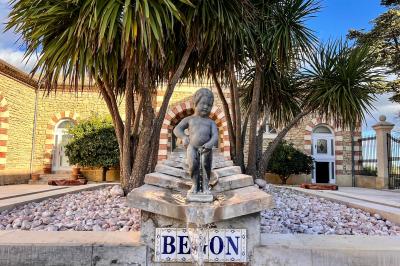 Vue d'un bassin avec toboggans aquatiques, entouré de végétation, de rochers et de jarres décoratives.