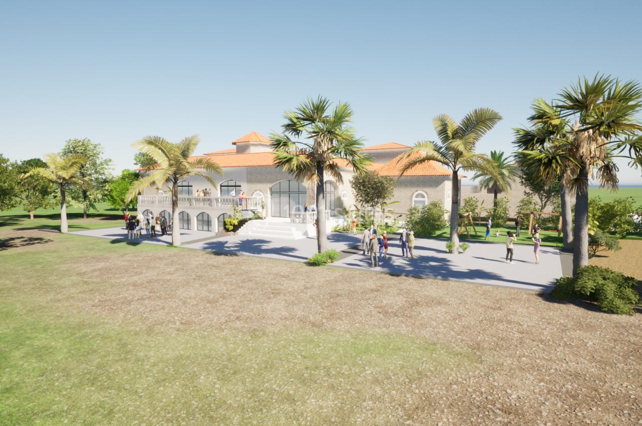 Vue d'un bâtiment élégant avec toit en tuiles, entouré de palmiers et d'un jardin, avec des personnes sur une terrasse.