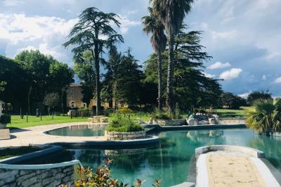Vue d'un bassin avec toboggans aquatiques, entouré de végétation, de rochers et de jarres décoratives.