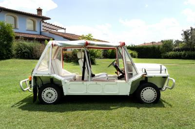 Vue latérale intérieure d'une voiture décapotable vintage avec sièges blancs bordés de rouge et toit en toile.