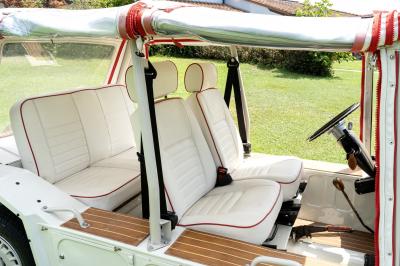 Voiture décapotable vintage avec intérieur en cuir blanc, vue de côté, stationnée sur une pelouse.
