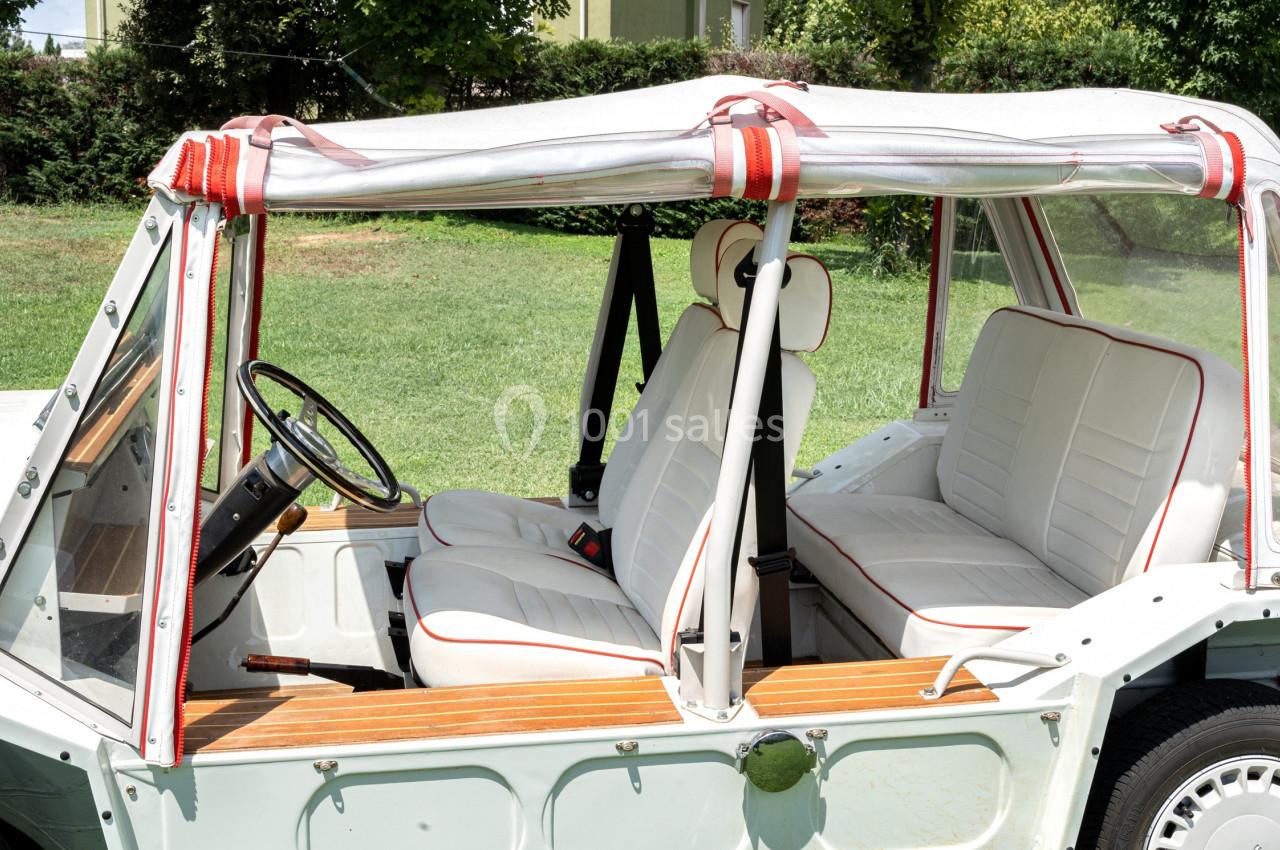 Voiture décapotable vintage avec intérieur en cuir blanc, vue de côté, stationnée sur une pelouse.