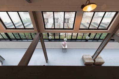 Escalier en bois à côté d'une composition florale blanche, avec un piano et un tapis coloré en arrière-plan.