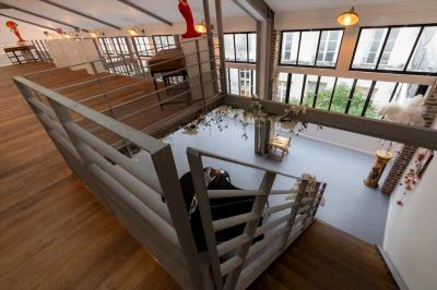 Escalier en bois à côté d'une composition florale blanche, avec un piano et un tapis coloré en arrière-plan.