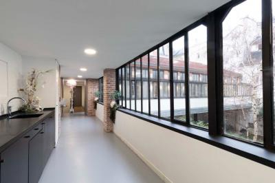 Escalier en bois à côté d'une composition florale blanche, avec un piano et un tapis coloré en arrière-plan.