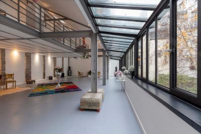 Escalier en bois à côté d'une composition florale blanche, avec un piano et un tapis coloré en arrière-plan.