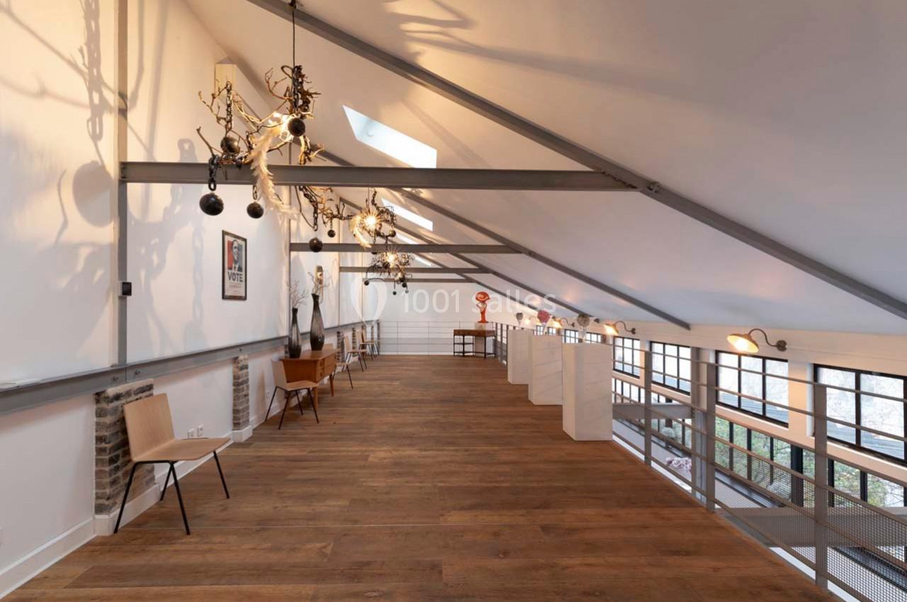 Intérieur d'un loft avec mezzanine, parquet en bois, mobilier minimaliste et grandes fenêtres laissant entrer la lumière.