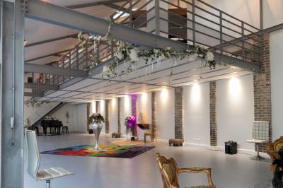 Escalier en bois à côté d'une composition florale blanche, avec un piano et un tapis coloré en arrière-plan.