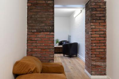 Escalier en bois à côté d'une composition florale blanche, avec un piano et un tapis coloré en arrière-plan.