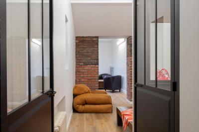 Escalier en bois à côté d'une composition florale blanche, avec un piano et un tapis coloré en arrière-plan.