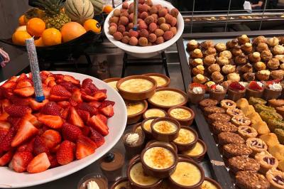 Lit double avec linge de lit jaune et blanc, éclairé par deux appliques murales, devant un tableau de fleurs.