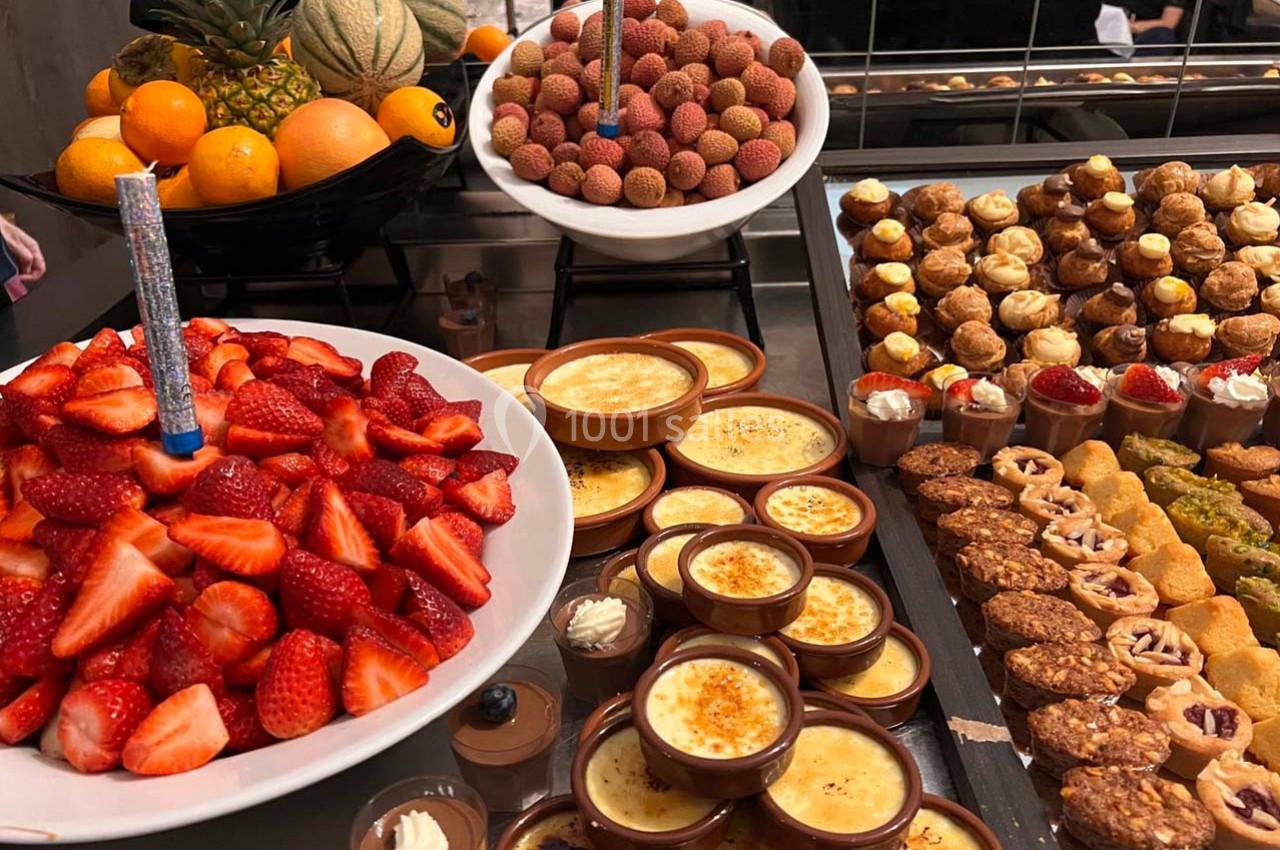 Assortiment de desserts variés avec fruits frais, crèmes brûlées, choux, tartelettes et pâtisseries sur un buffet.