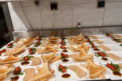 Lit double avec linge de lit jaune et blanc, éclairé par deux appliques murales, devant un tableau de fleurs.